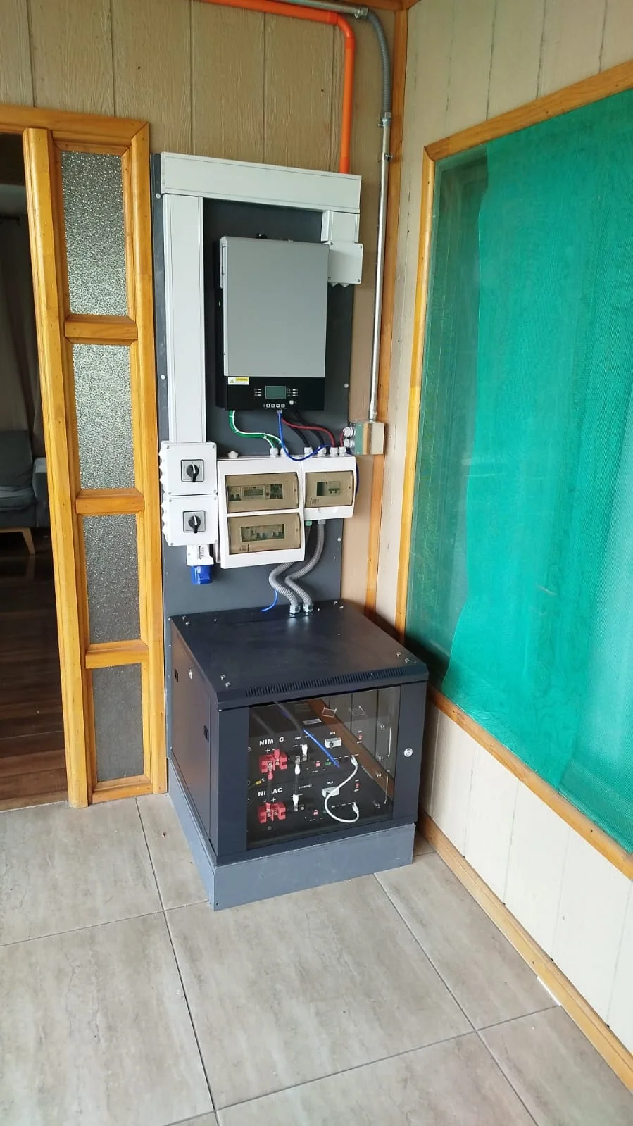 Vista completa del equipamiento instalado en el interior de una vivienda, con el gabinete de baterías en el suelo