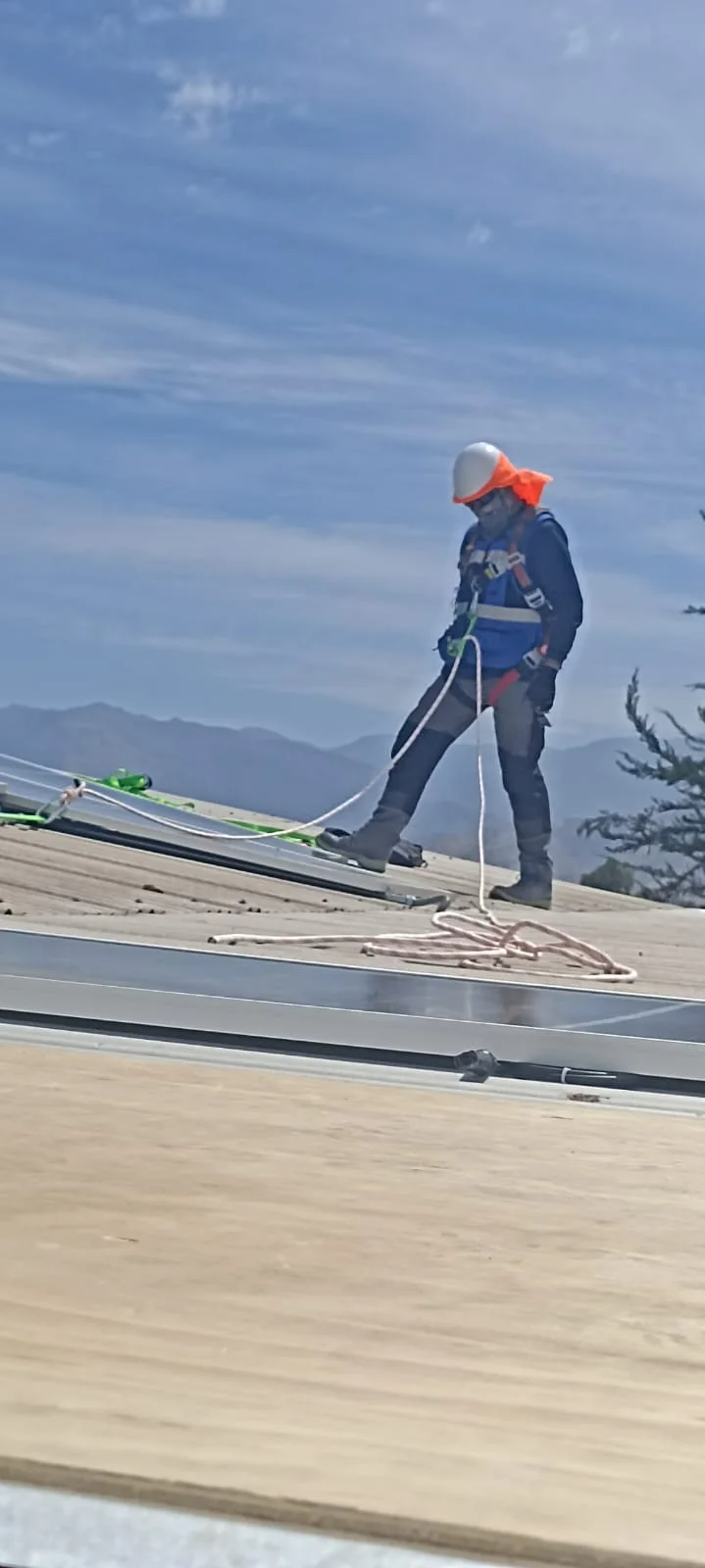 Instalador asegurado desplazándose sobre la cubierta de una vivienda