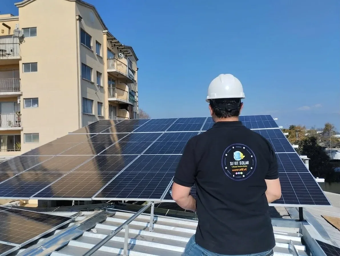 Técnico de SLF con casco revisando una instalación de paneles solares en un techo